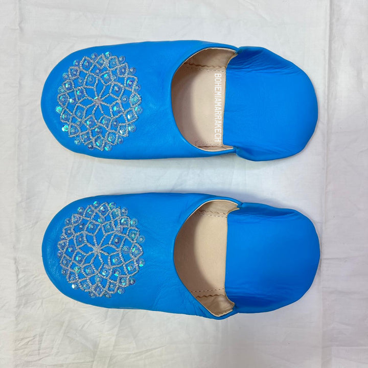 Traditional Moroccan leather babouche slippers in blue, featuring artisan beaded medallion design.