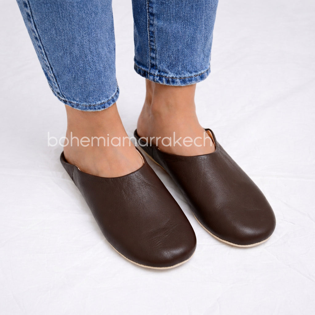 Dark brown Moroccan leather babouche slippers with plain minimalist design on wooden floor