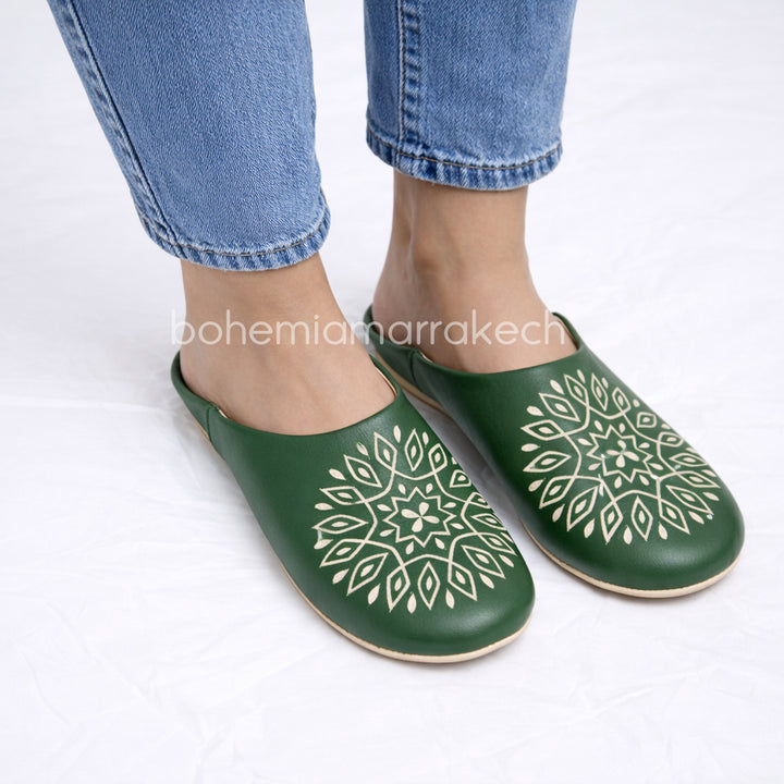 Handmade green Moroccan babouche slippers with stitched leather and carved traditional pattern on a white background