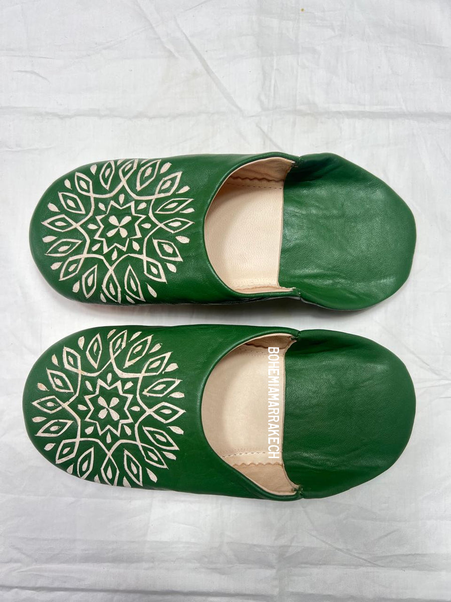 Handmade green Moroccan babouche slippers with stitched leather and carved traditional pattern on a white background