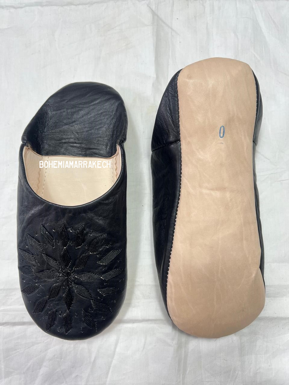 Black Moroccan babouche slippers with stitched geometric leather design on white background