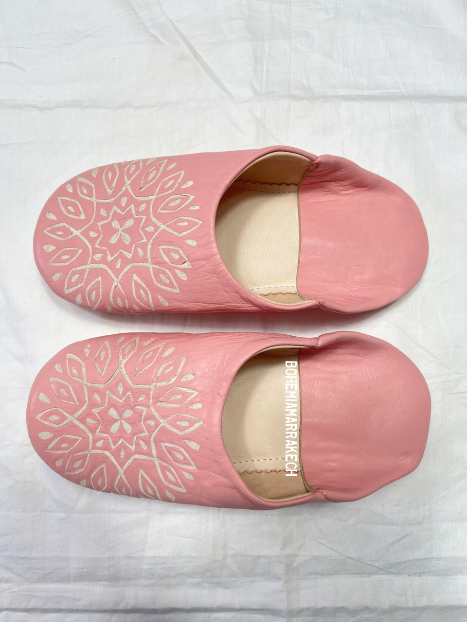 Handmade pink Moroccan babouche slippers with hand-carved geometric leather design on a white background
