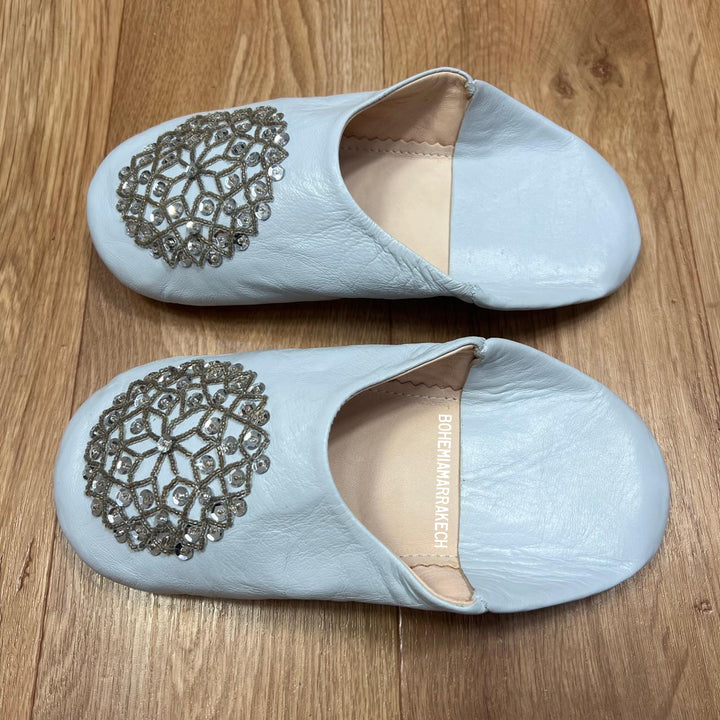 Light blue Moroccan babouche slippers handmade in leather with beaded geometric design, worn on model