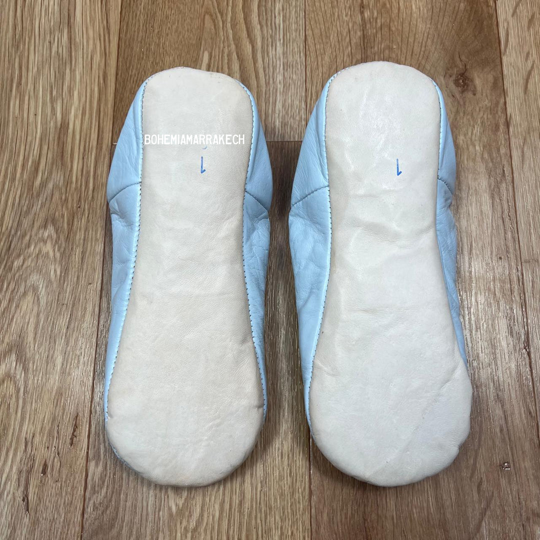 Light blue Moroccan babouche slippers handmade in leather with beaded geometric design, worn on model