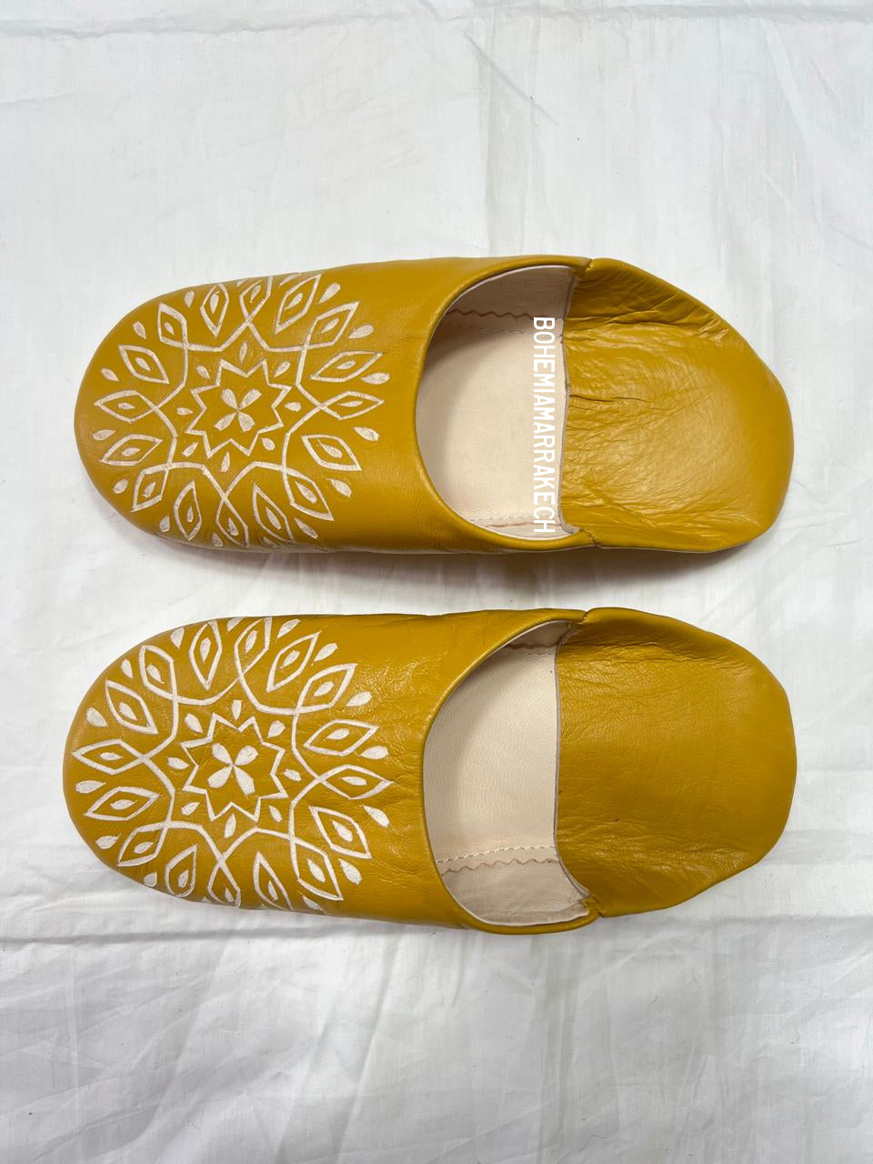 Mustard yellow Moroccan babouche slippers with carved geometric leather design on white background
