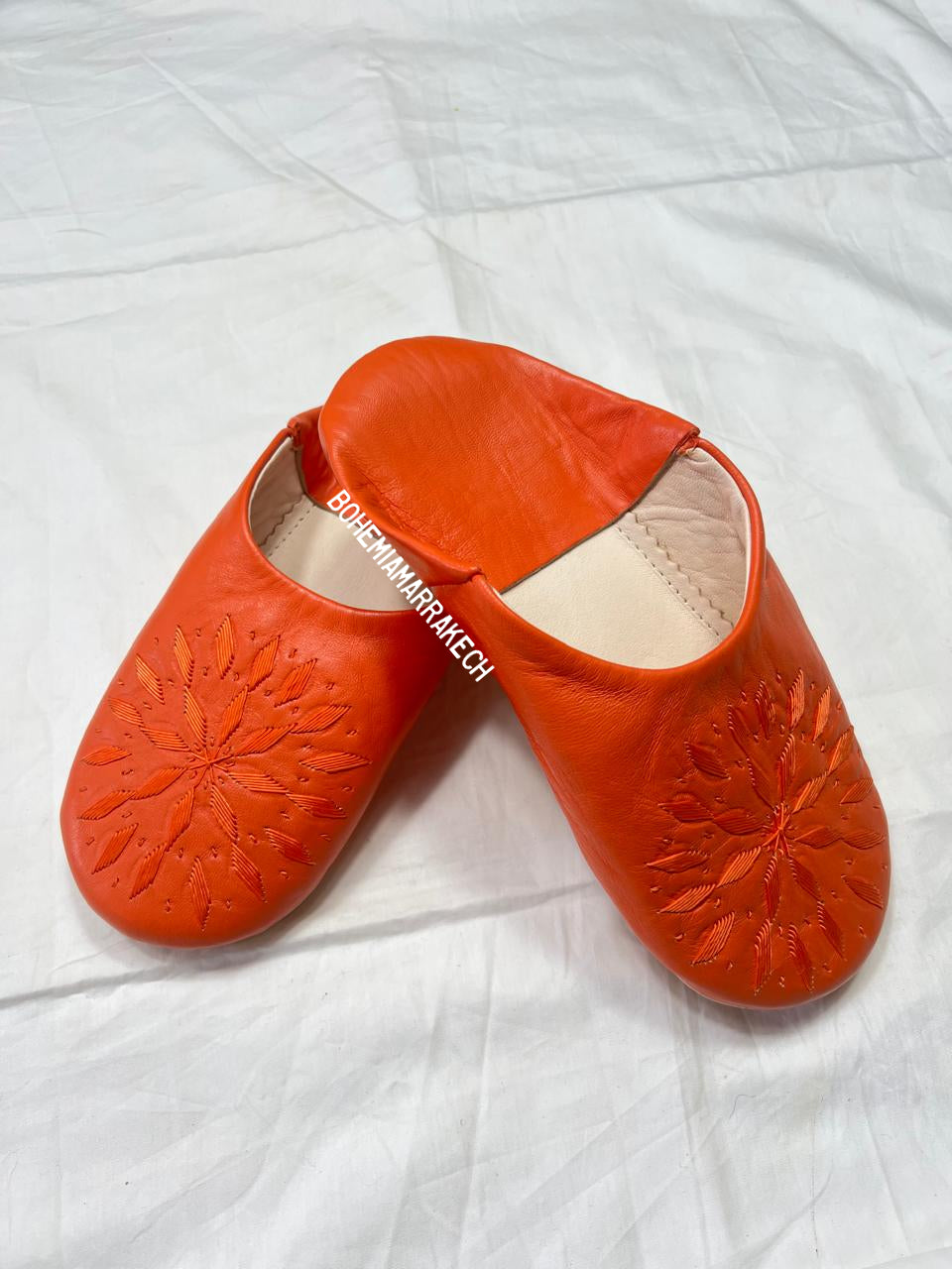Handmade Moroccan babouche slippers in orange leather with traditional hand-stitched design, fully hand-stitched by artisans.
