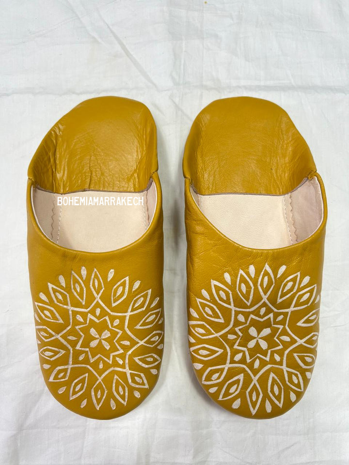Mustard yellow Moroccan babouche slippers with carved geometric leather design on white background
