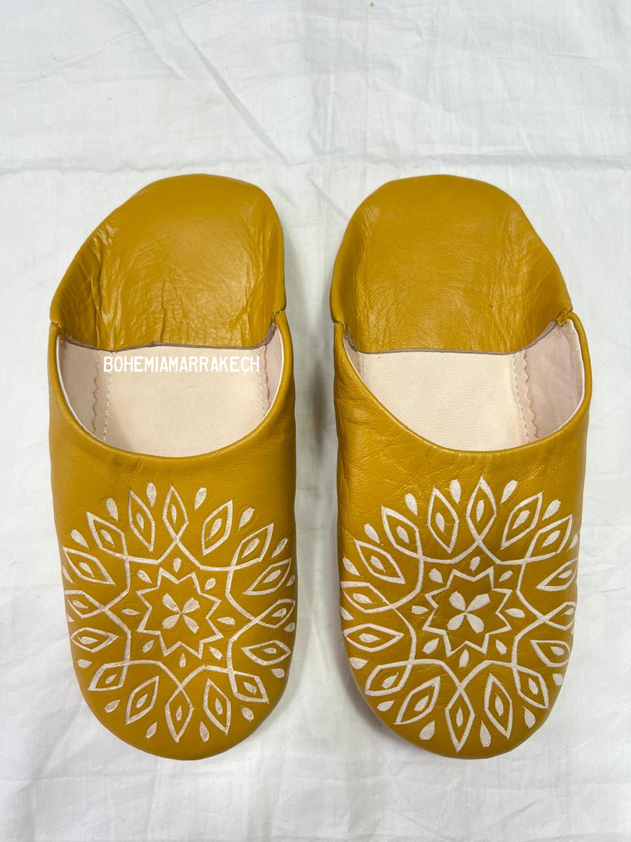 Mustard yellow Moroccan babouche slippers with carved geometric leather design on white background