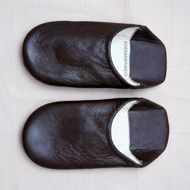 Dark brown Moroccan leather babouche slippers with plain minimalist design on wooden floor
