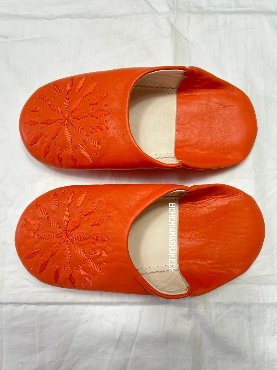 Handmade Moroccan babouche slippers in orange leather with traditional hand-stitched design, fully hand-stitched by artisans.