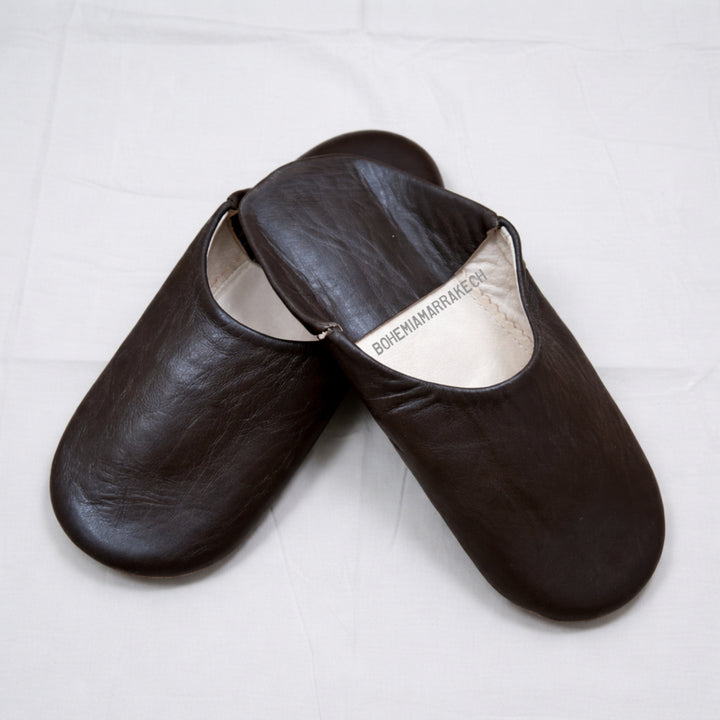 Dark brown Moroccan leather babouche slippers with plain minimalist design on wooden floor