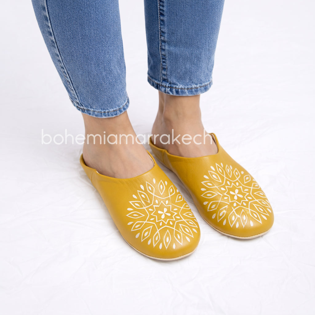 Mustard yellow Moroccan babouche slippers with carved geometric leather design on white background