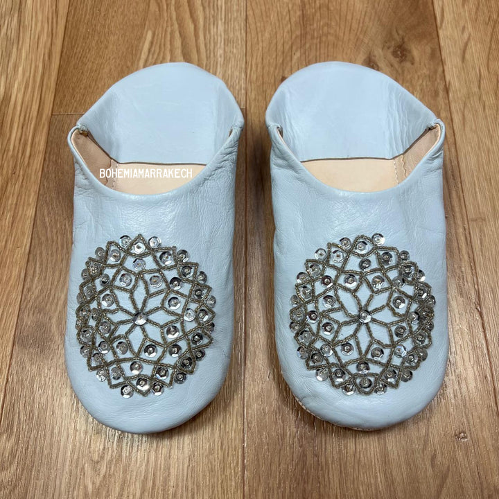 Light blue Moroccan babouche slippers handmade in leather with beaded geometric design, worn on model
