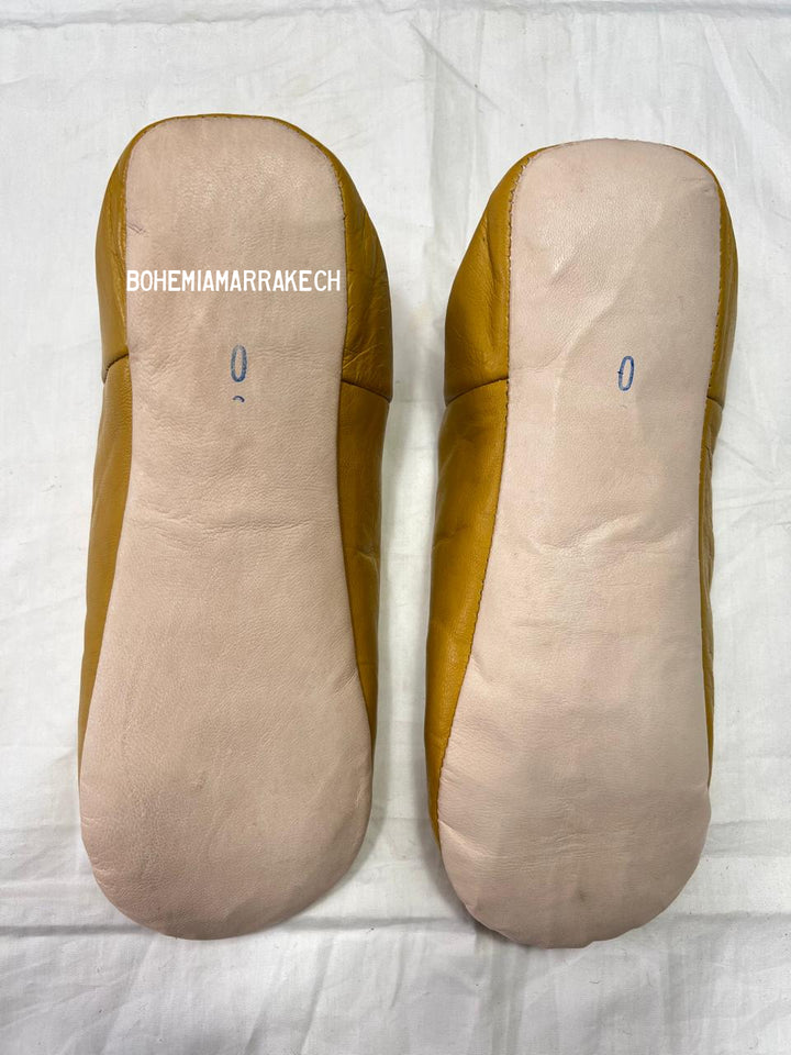 Mustard yellow Moroccan babouche slippers with carved geometric leather design on white background