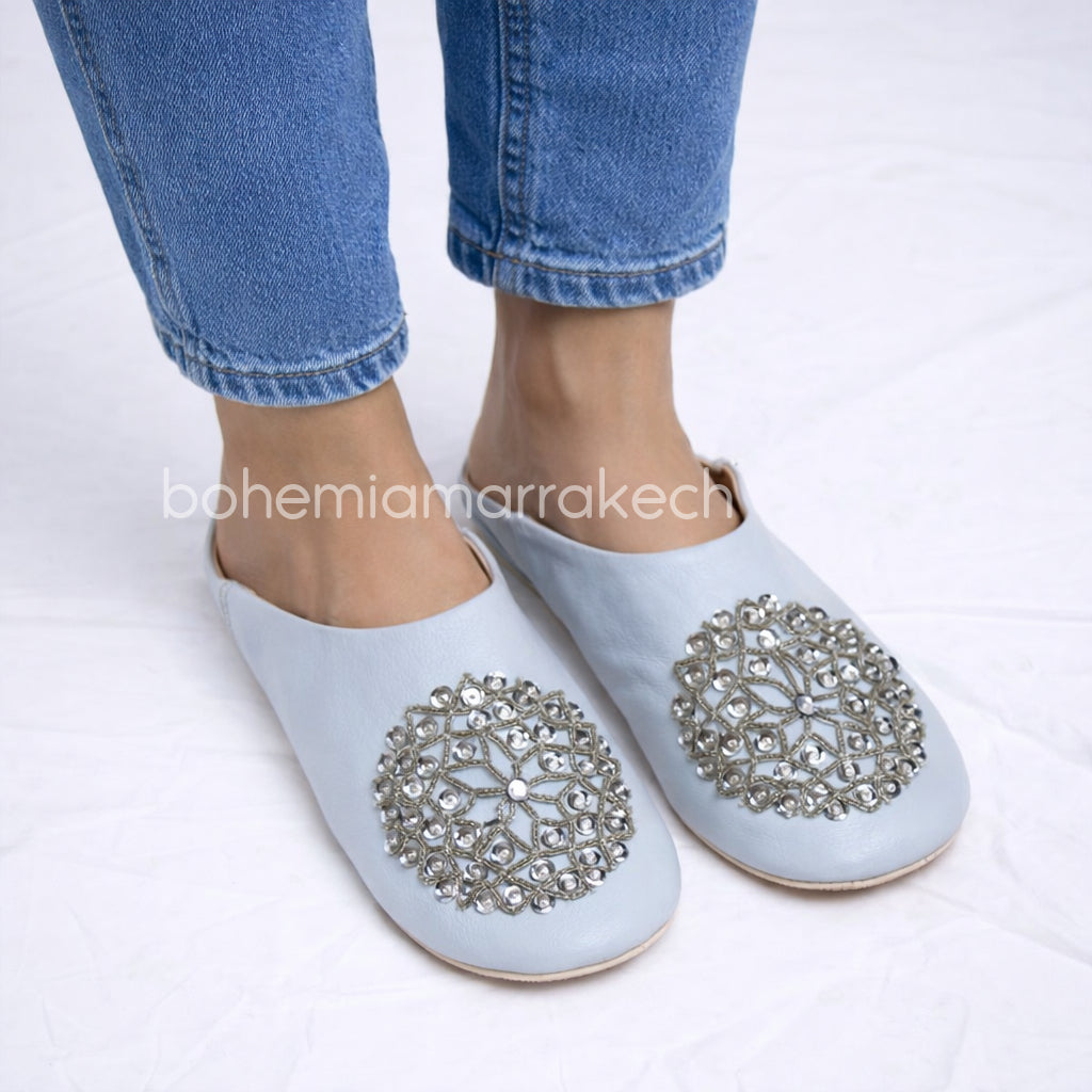 Light blue Moroccan babouche slippers handmade in leather with beaded geometric design, worn on model