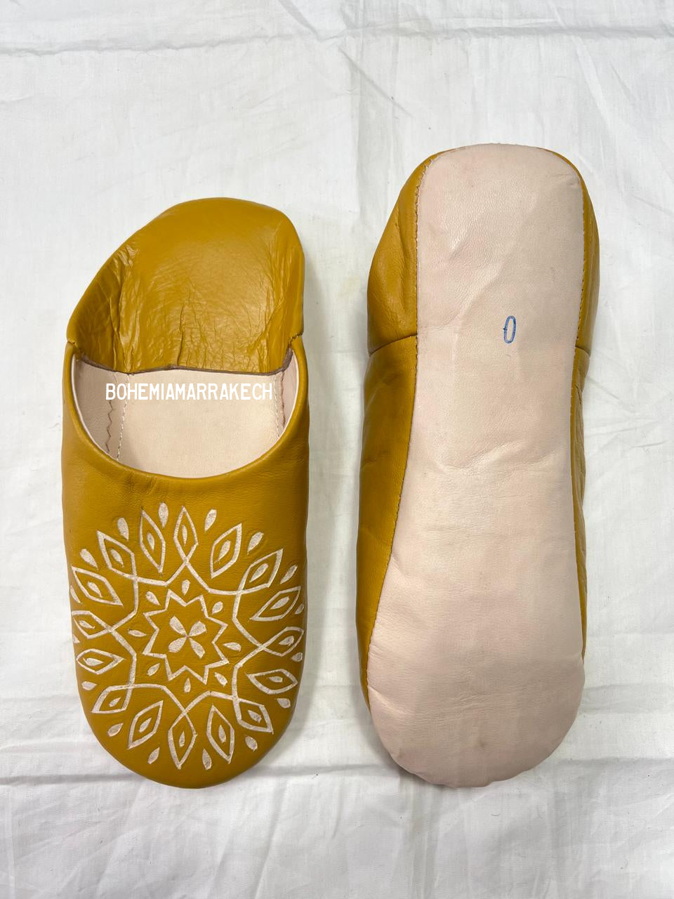 Mustard yellow Moroccan babouche slippers with carved geometric leather design on white background