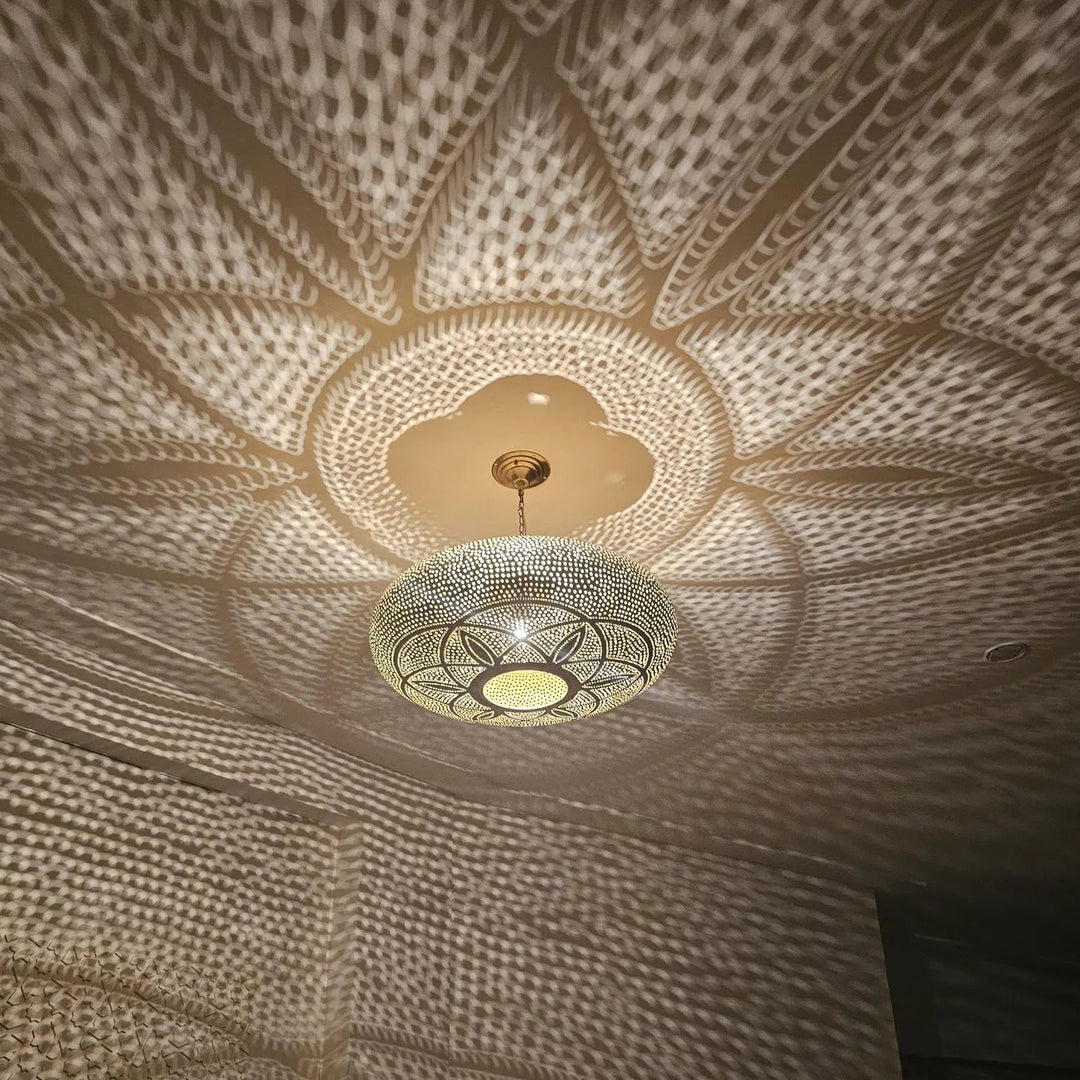 Decorative ceiling light fixture casting intricate shadows on a textured ceiling.