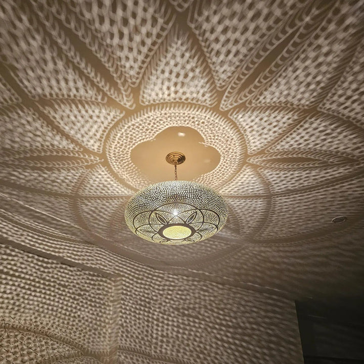 Decorative ceiling light fixture casting intricate shadows on a textured ceiling.