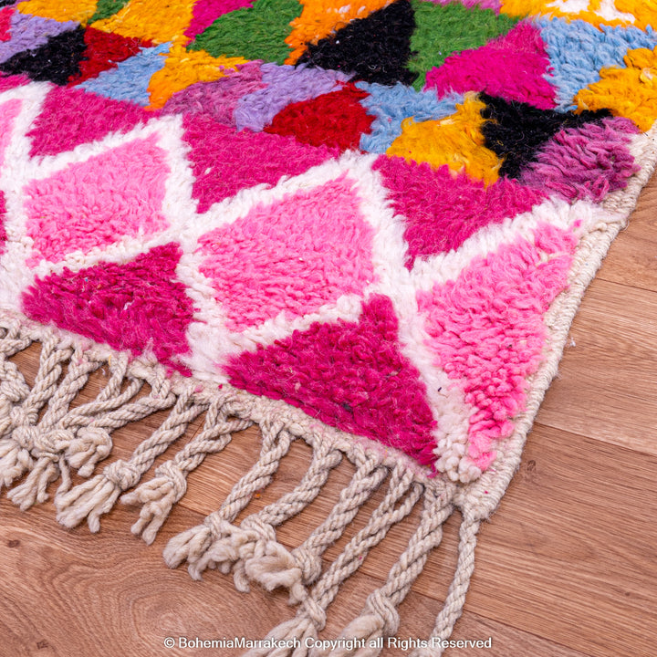 Large colorful Moroccan rug with bold geometric Berber patterns in pink, orange, blue, and yellow