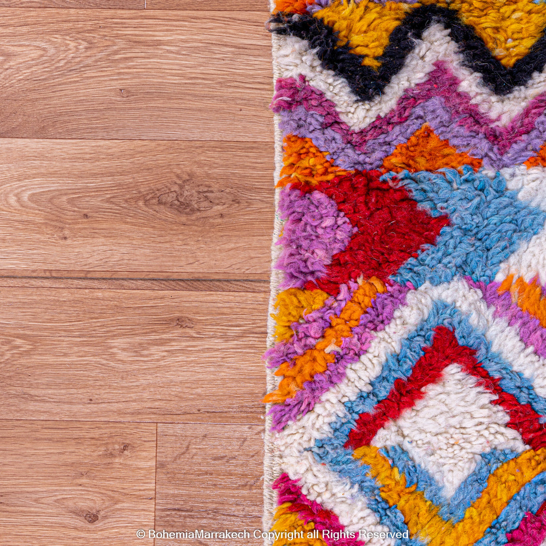Large colorful Moroccan rug with bold geometric Berber patterns in pink, orange, blue, and yellow