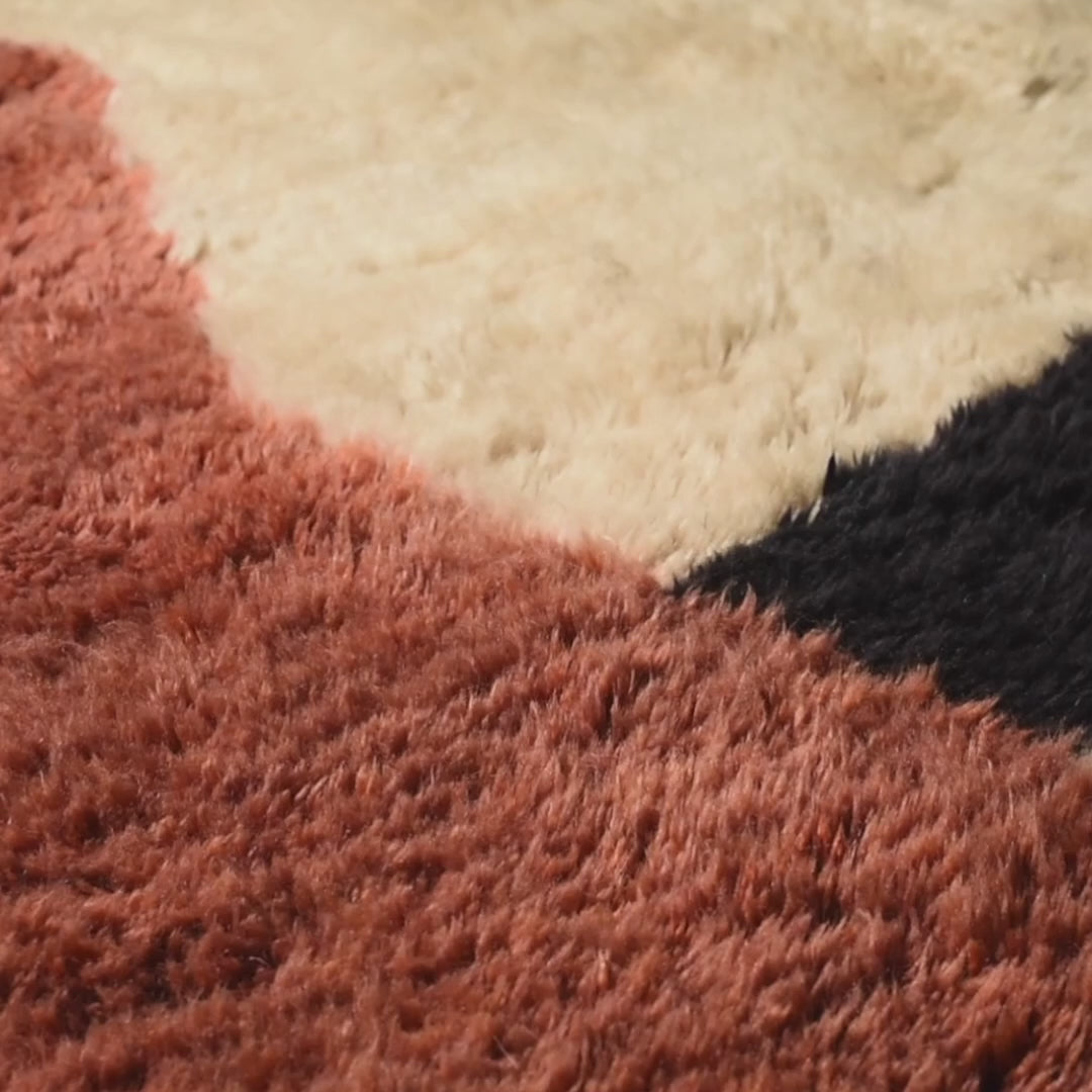 Close-up of a custom Moroccan rug with terracotta, ivory, and black wool texture, perfect for contemporary home decor.