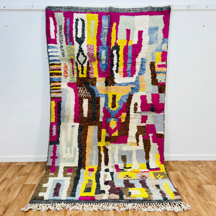 Colorful Moroccan wool rug with abstract geometric patterns in magenta, mustard, and sky blue, handmade by Berber artisans.