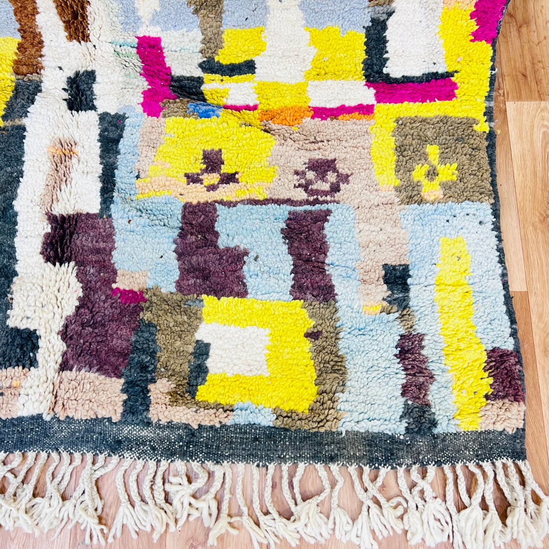 Colorful Moroccan wool rug with abstract geometric pattern in magenta, mustard yellow, sky blue, and soft grey.