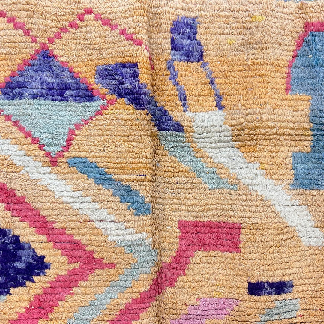 Vintage Moroccan wool rug with abstract geometric Berber design in warm ochre, pink, blue and green tones, handwoven in Morocco.