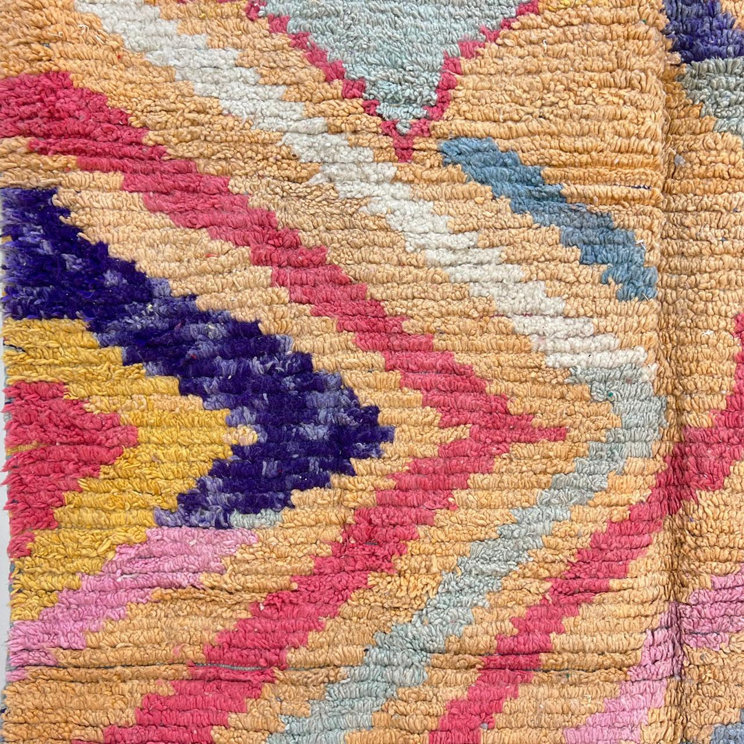 Vintage Moroccan wool rug with abstract geometric Berber design in warm ochre, pink, blue and green tones, handwoven in Morocco.