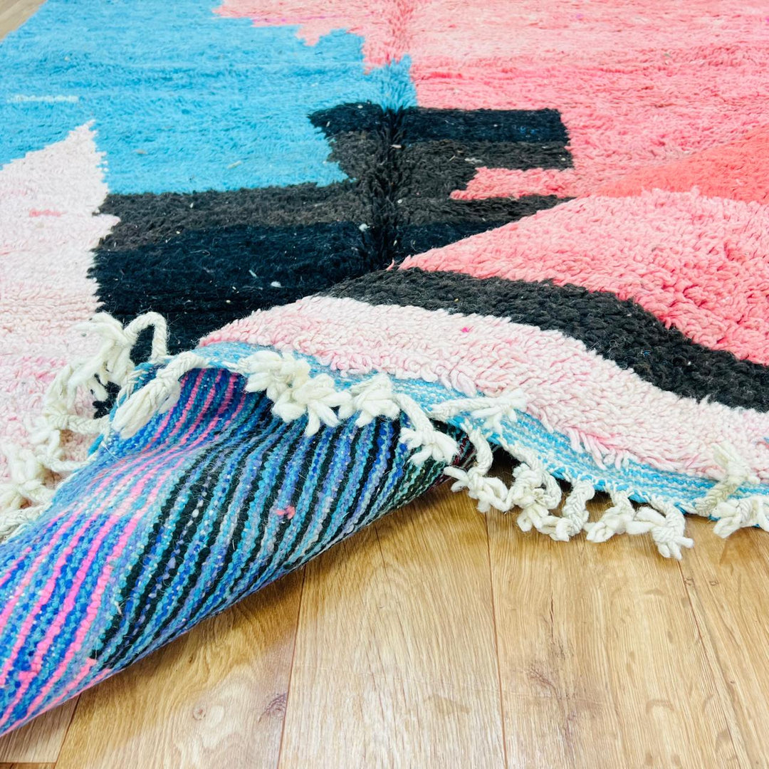 Vintage Moroccan wool rug with abstract coral pink, blue, and black color-block geometric design, handwoven Berber carpet from Morocco.