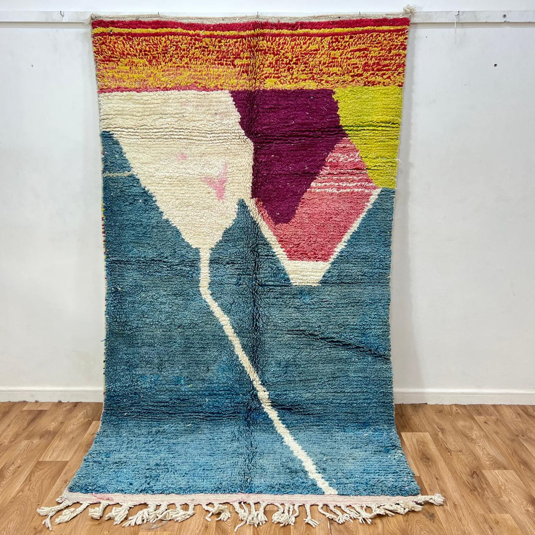Vintage Moroccan wool rug BM31 – handmade blue, pink, and yellow abstract geometric design (253 × 148 cm).