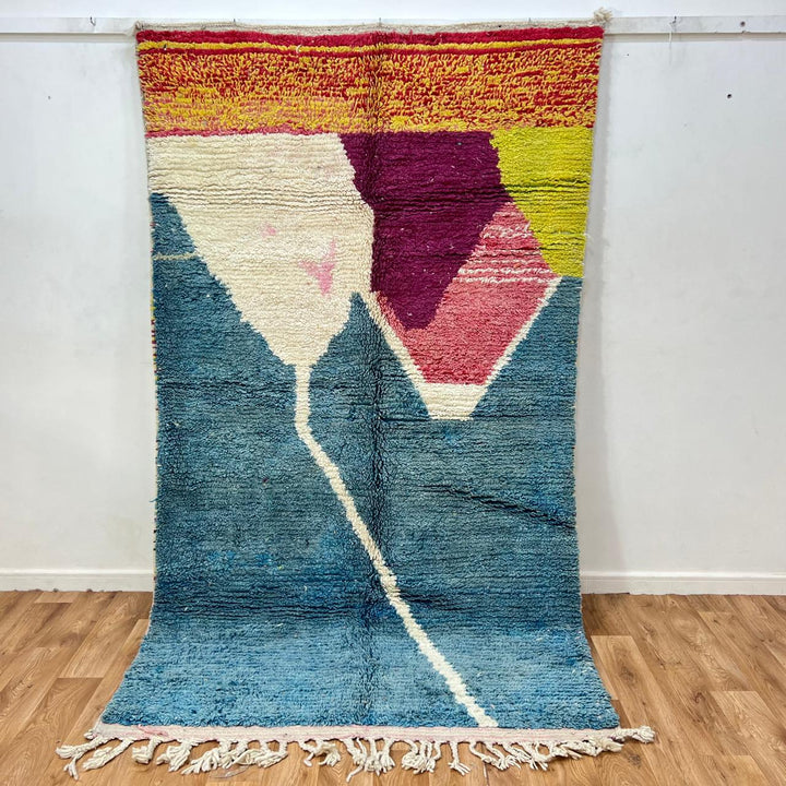 Vintage Moroccan wool rug BM31 – handmade blue, pink, and yellow abstract geometric design (253 × 148 cm).