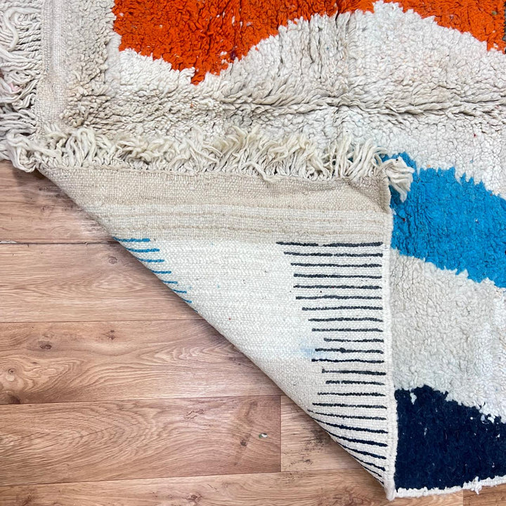 Vintage Moroccan wool rug 136 – handmade wavy pattern in blue, orange, red, and gray tones (221 × 150 cm).