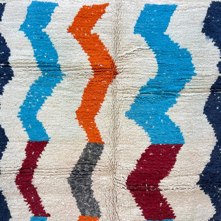 Vintage Moroccan wool rug 136 – handmade wavy pattern in blue, orange, red, and gray tones (221 × 150 cm).