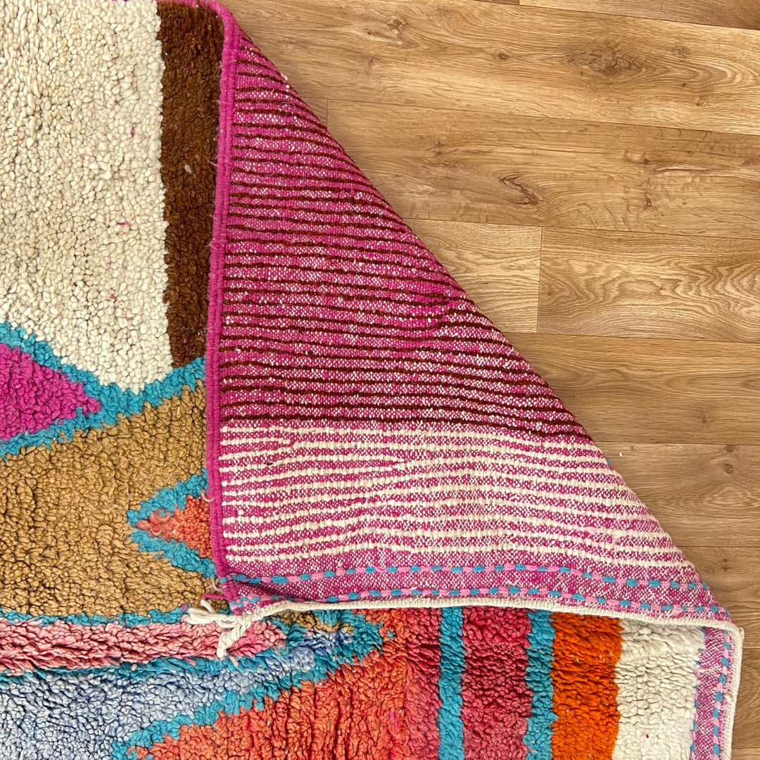 Vintage Moroccan wool rug with abstract Berber figure in turquoise and warm pink, sand and brown tones, handwoven in Morocco