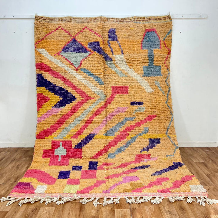 Vintage Moroccan wool rug with abstract geometric Berber design in warm ochre, pink, blue and green tones, handwoven in Morocco.