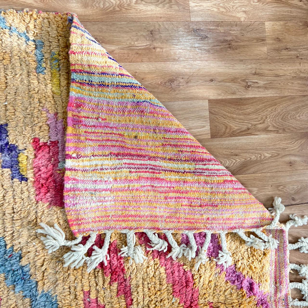 Vintage Moroccan wool rug with abstract geometric Berber design in warm ochre, pink, blue and green tones, handwoven in Morocco.
