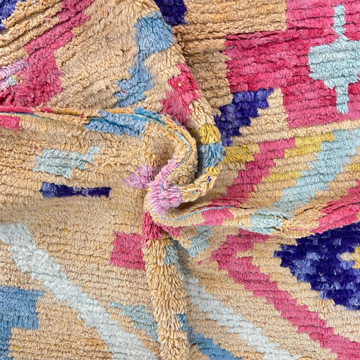 Vintage Moroccan wool rug with abstract geometric Berber design in warm ochre, pink, blue and green tones, handwoven in Morocco.